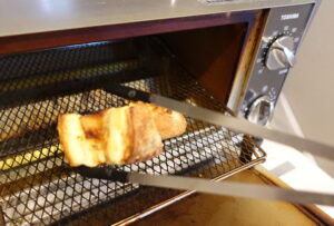 トースターから熱々のパンを取り出すところの写真
