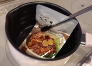 熱々の鍋からレトルト食品を採りだすところの写真